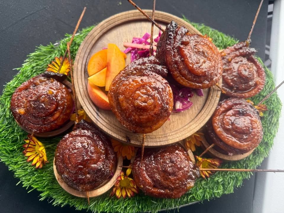 Peach Bourbon glazed pork belly lollipops arranged on a wooden platter